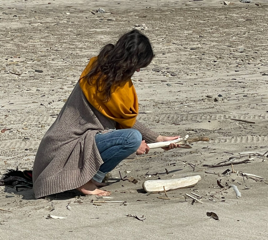 Hannah choosing driftwood for the altar at Lake Erie, the place where the sky spun.
